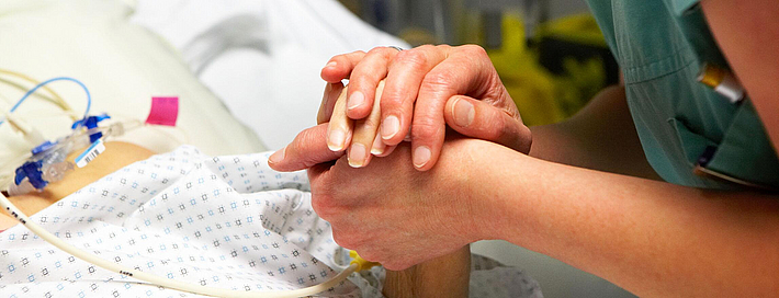 Pflegerin hält Patientenhand